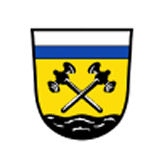 Wappen mit goldenem Hintergrund: in der Mitte zwei gekreuzte schwarze Hämmer, oben ein blauer Balken unter silbernem Feld, unten ein schwarzer Wellenfuß.