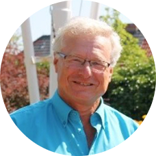 Älterer Mann mit hellem Haar und Brille, lächelt im Freien bei sonnigem Wetter – freundliches Porträt im Garten.